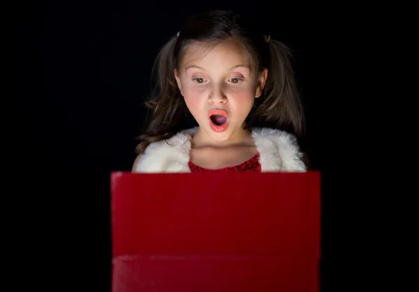 A pretty little girl opens her Christmas present — Stock Photo, Image