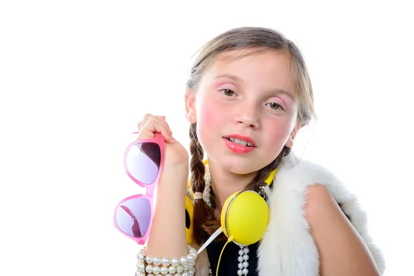 Une jolie petite fille aux lunettes roses et écouteurs jaunes — Photo