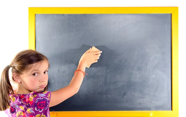 A little girl with pigtails writes on a blackboard — Stock Photo, Image