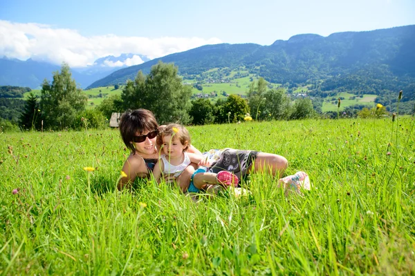 Eine schöne Mutter und Tochter im Gras liegend — Stockfoto