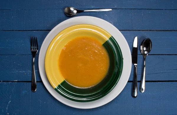 Płyta z zupa dyniowa na niebieskim drewnianym stołem — Zdjęcie stockowe
