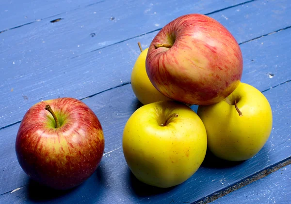 Mehrere Äpfel auf einen blau bemalten Tisch gelegt — Stockfoto