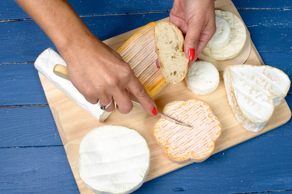 Een vrouw die een stuk van Franse kaas snijden — Stockfoto