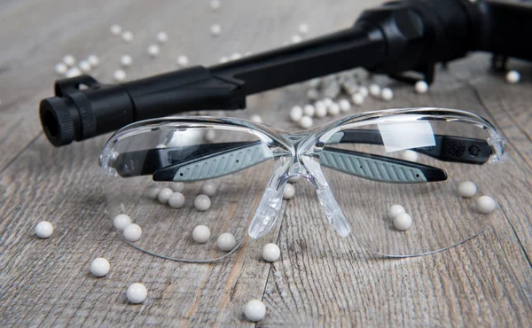 Airsoft gun with glasses and lot of bullets — Stock Photo, Image