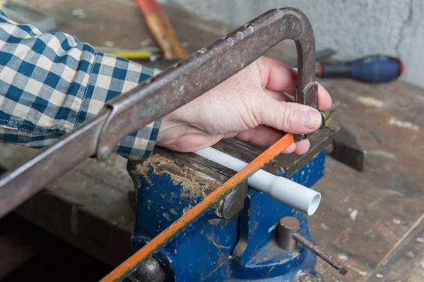 Uomo tagliato tubo in PVC con una sega a mano — Foto Stock