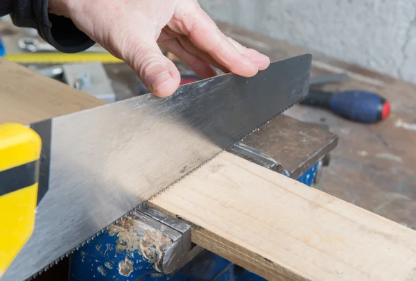 En arbetare skära en planka av trä med en hand såg — Stockfoto