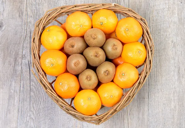 Owoce kiwi i tangerins w wiklinowym koszu — Zdjęcie stockowe