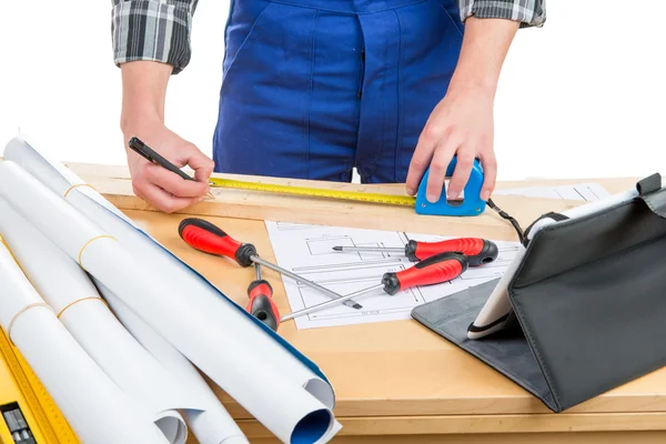 A worker measuring a board with a tape measure — Stock Photo, Image