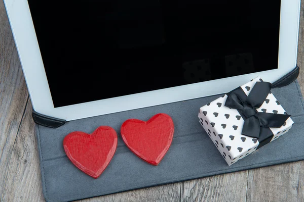 Ein Herz und ein Geschenk mit einem digitalen Tablet — Stockfoto