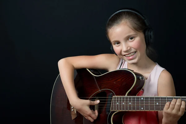 A pretty little girl whit headphones playing guitar — Stock Photo, Image