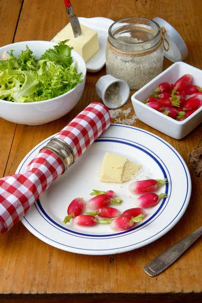 Plate with radish and butter on a table — Stock Photo, Image