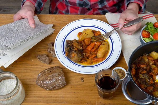 Un homme mange de la carotte de bœuf et lit un journal — Photo