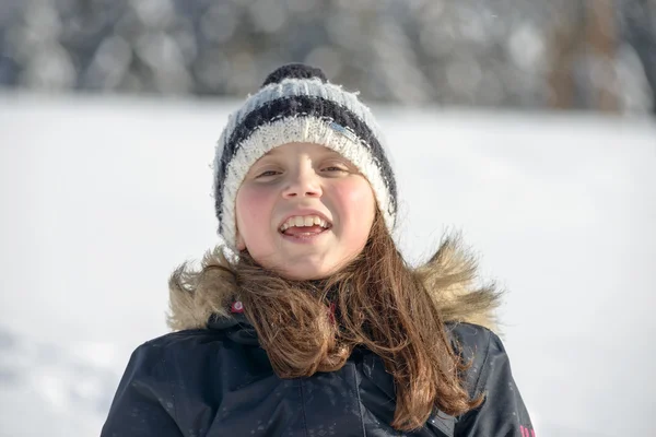 En leende flicka med en mössa i snön — Stockfoto