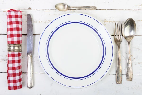 Teller mit Silberbesteck auf einem alten weißen Tisch — Stockfoto