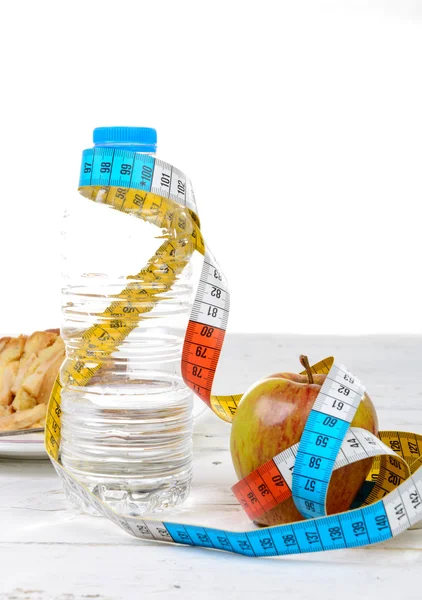 Botella de agua y manzana con cinta métrica —  Fotos de Stock