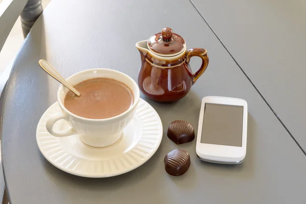 Xícara de chocolate quente com um telefone — Fotografia de Stock