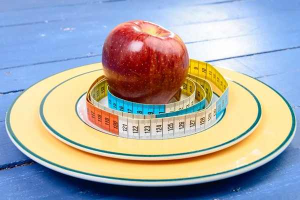 One meter ribbon around apple in the plate — Stock Photo, Image