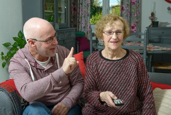 Eine ältere Mutter mit ihrem Sohn vor dem Fernseher — Stockfoto