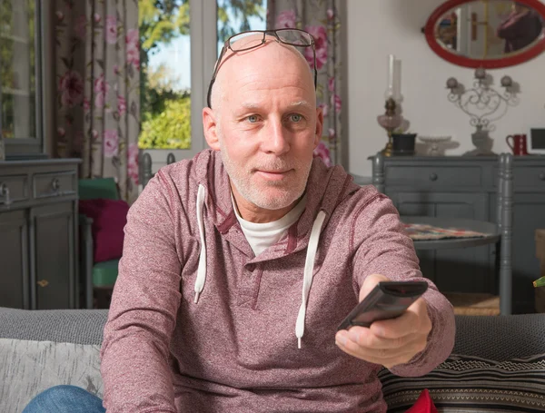 Un homme âgé regardant la télévision dans son canapé — Photo