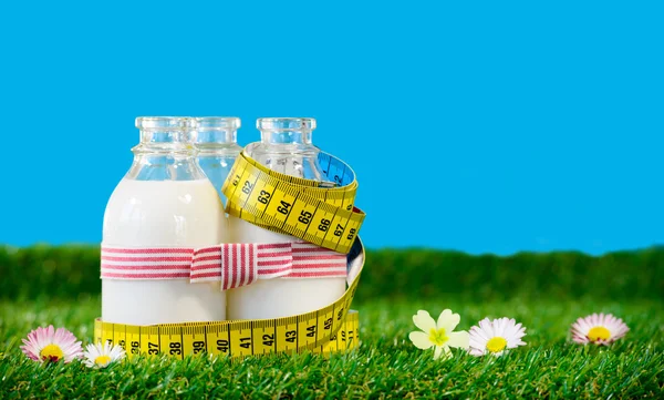 Three small bottles of milk with a tape measure — Stock Photo, Image