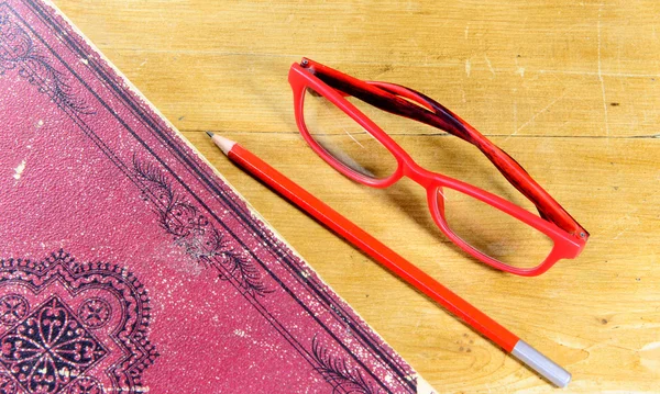 Livre, stylo et paire de lunettes rouges — Photo