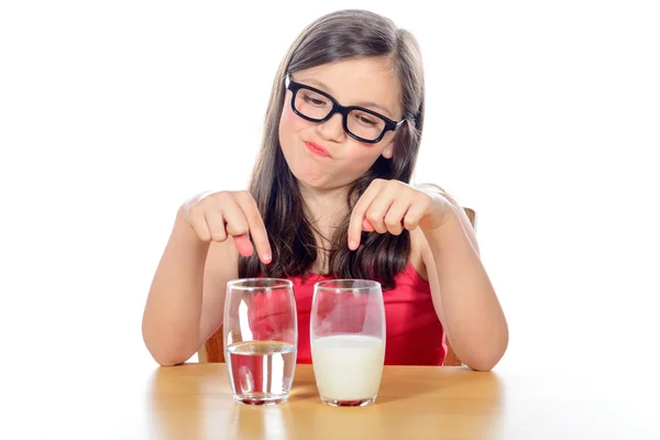 Uma menina tem uma escolha entre água e leite — Fotografia de Stock