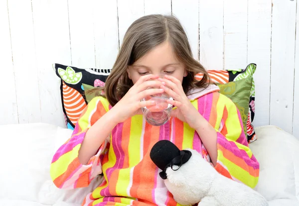 Uma menina doente bebendo um copo de água — Fotografia de Stock