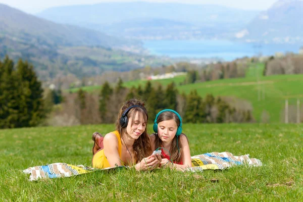 Mom and daughter listening music in nature — Stock Photo, Image