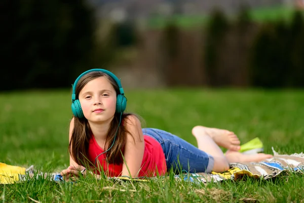 Una chica muy joven escuchando música en la naturaleza —  Fotos de Stock