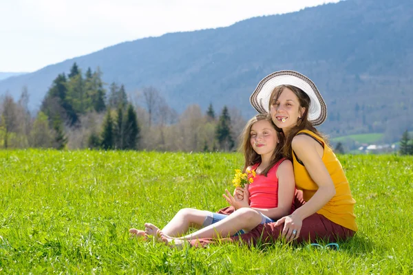 Una madre e sua figlia con un fiore in bocca — Foto Stock