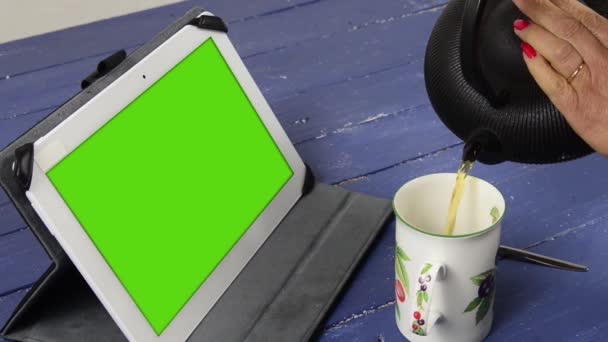 Женщина пьет чай с цифровым планшетом с зеленым экраном — стоковое видео
