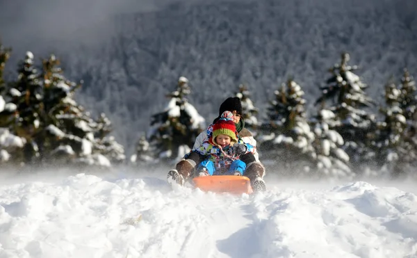 Un niño pequeño en trineo en la nieve — Foto de Stock