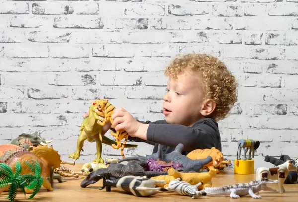 Een klein kind speelt met speelgoed dieren — Stockfoto