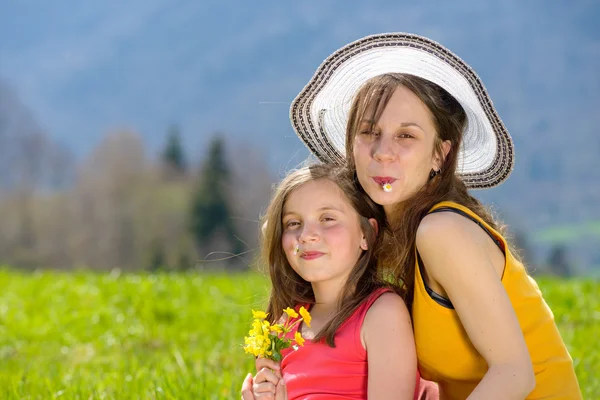 Una madre y su hija con una flor en la boca — Foto de Stock