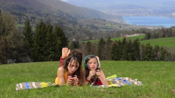Мама и дочь слушают музыку на природе — стоковое видео