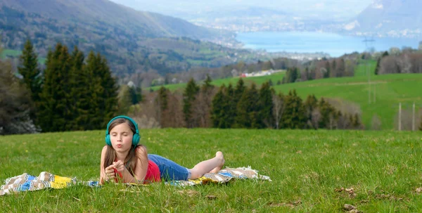En ganska ung flicka lyssna på musik med hörlurar — Stockfoto