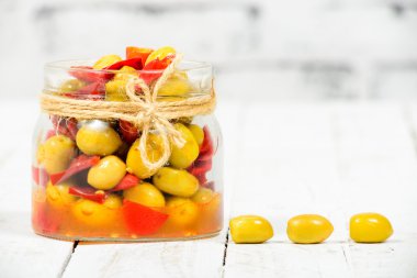 Cam Kavanoz zeytin ve beyaz masada biber ile
