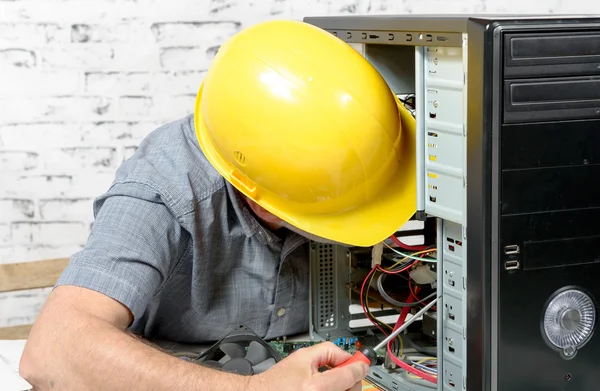A technician repairing a computer with yellow helmet — Stock Photo, Image