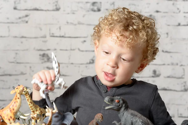 Een klein kind speelt met speelgoed dieren — Stockfoto