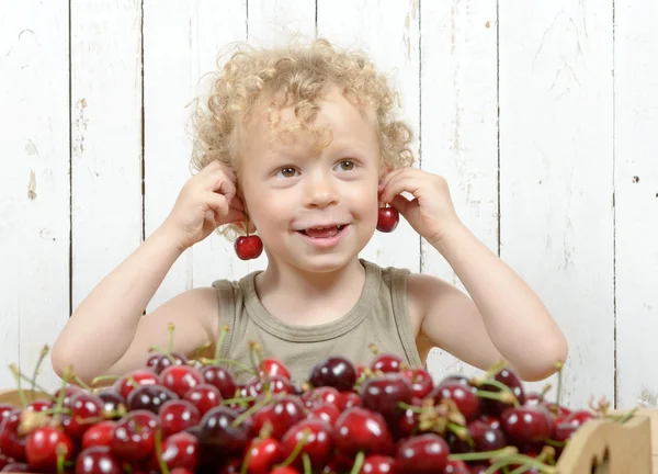 Um pequeno menino loiro comendo cerejas — Fotografia de Stock