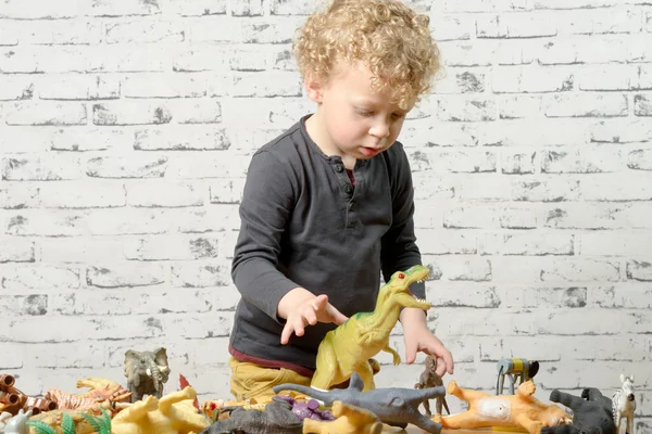 A little child plays with toys animals — Stock Photo, Image