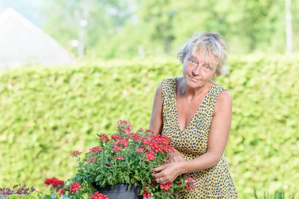 Una mujer bonita de mediana edad cuidado flores — Foto de Stock