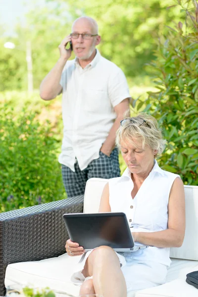 A man on phone and his wife on  computer — Stock Photo, Image