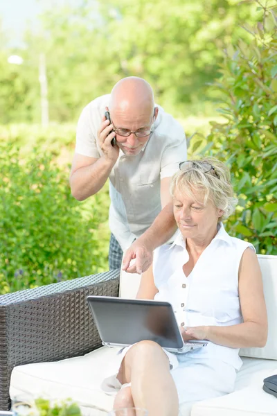 A man on phone and his wife on  computer — Stock Photo, Image