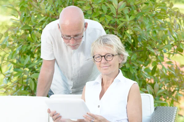 A couple of seniors look at a digital tablet — Stock Photo, Image