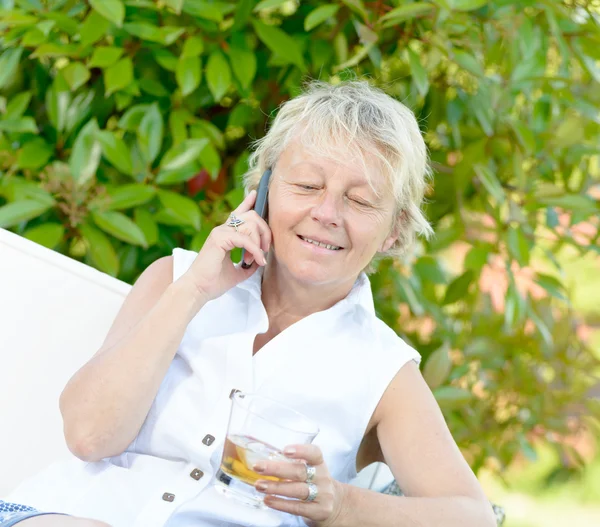 Een vrouw zitten op telefoon met een drankje — Stockfoto