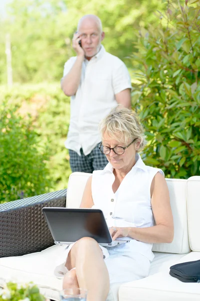 A man on phone and his wife on  computer — Stock Photo, Image