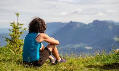 woman sitting on cliff and  looking at landscape