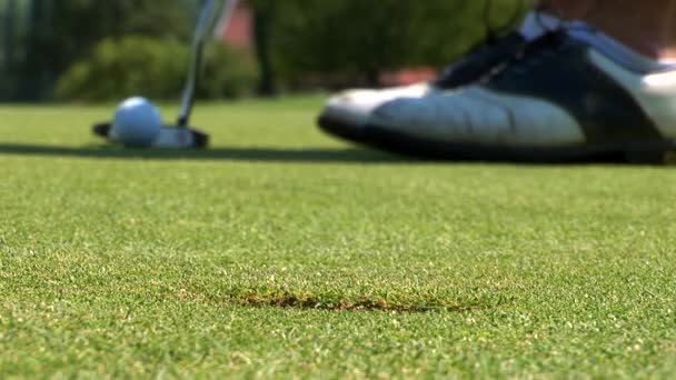 Zbliżenie golfisty za pomocą miotacza, aby zatopić krótki putt w otworze, — Wideo stockowe