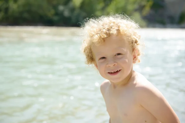 Porträtt av en ung blond pojke spelar i vatten — Stockfoto